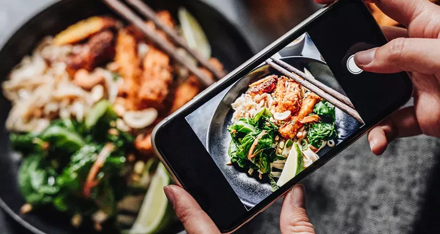 Pessoa fotografando um prato de comida com o celular para análise nutricional pelo Essentia Scan